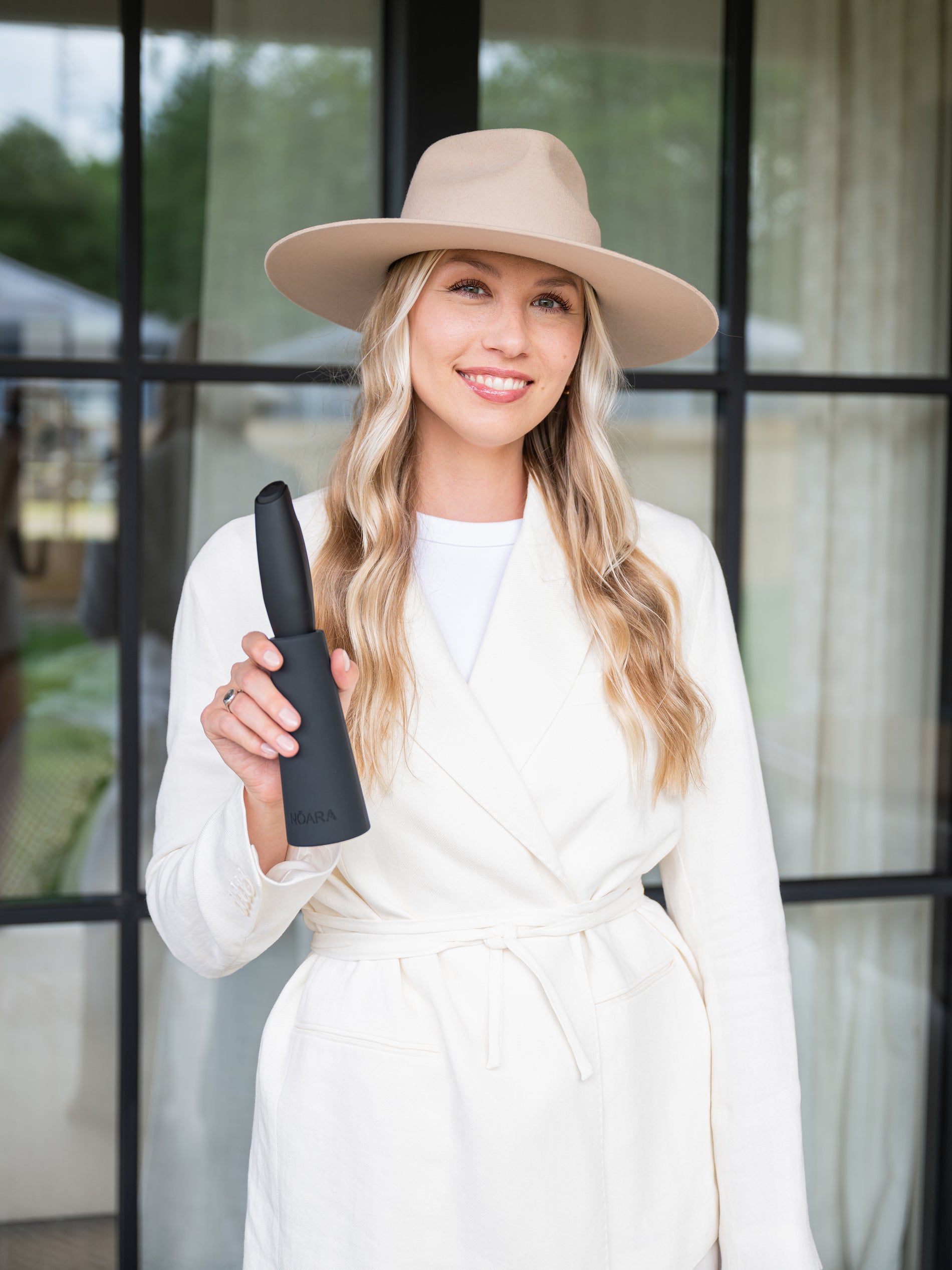 Grete, founder of NŌARA, holding black handheld frother and silicone stand