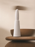 White NŌARA handheld frother and silicone stand placed in a natural outdoor setting